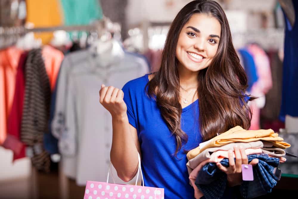 women on a clothing store holding clothes and shopping bag