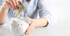Woman saving money into piggy bank