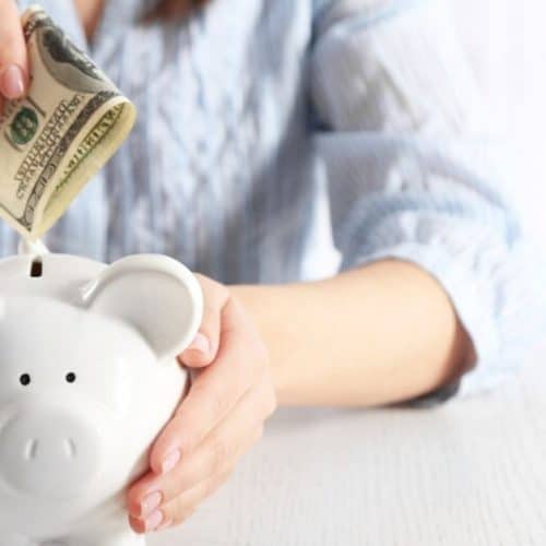 Woman saving money into piggy bank