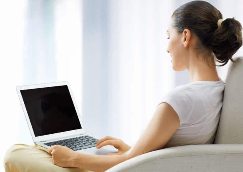 women sitting on a couch and holding a laptop