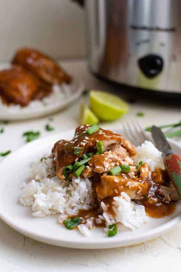 Crockpot Teriyaki Chicken served in a white plate next to a crockpot and a lemon cut in half