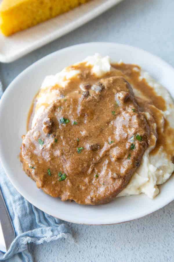 Crockpot Cube steak served over mashed potatoes in a white bowl