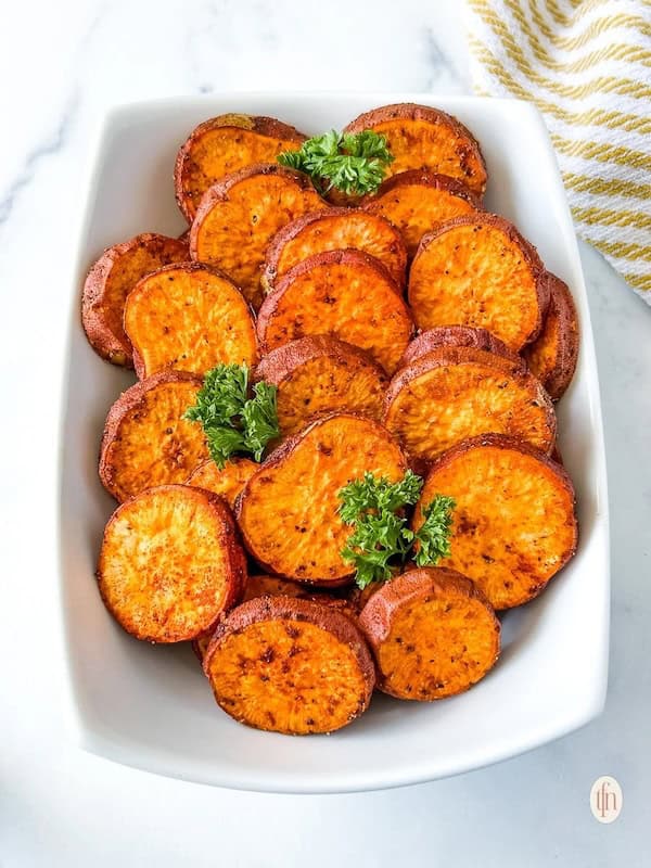 Baked sweet potato slices with garlic and parmesan on a baking sheet — vibrant easy Christmas side dish.
