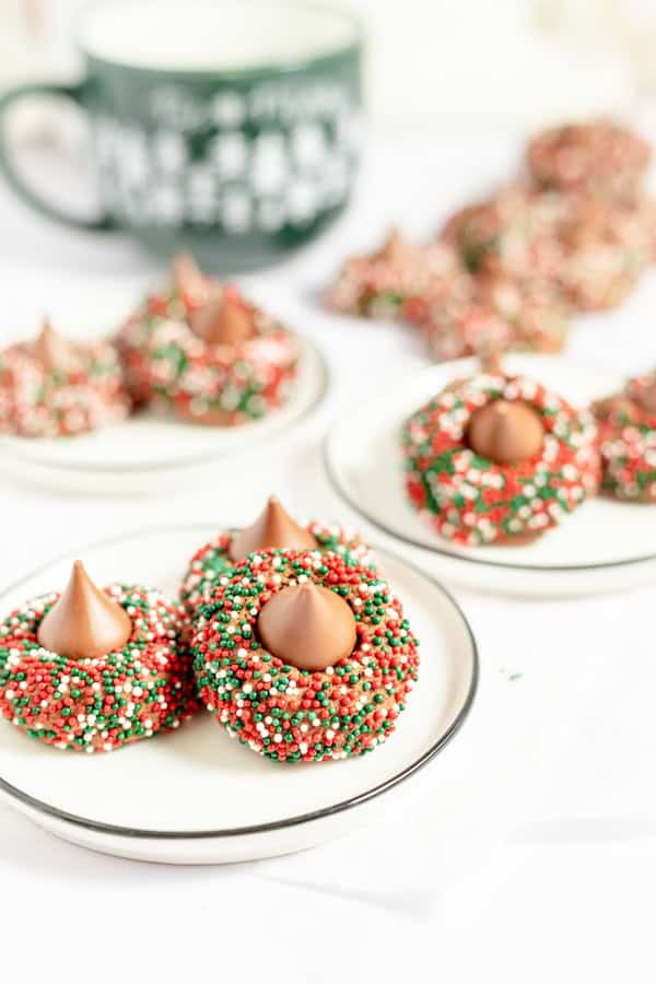 Chocolate blossom cookies topped with Hershey’s Kisses and rolled in red and green sprinkles on a holiday tray — classic homemade Christmas cookies.