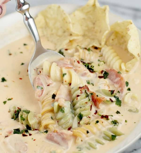 Bowl of festive tomato and pasta soup garnished with herbs for a cozy Christmas dinner.