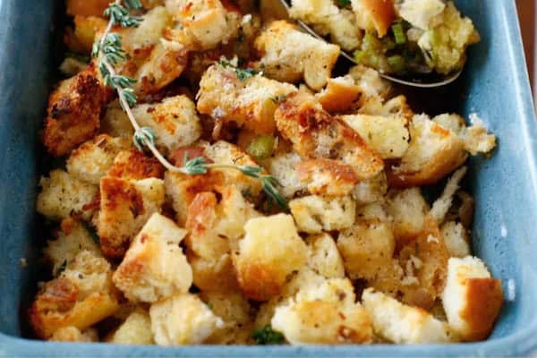 Close-up of classic bread stuffing with herbs and celery in a white casserole dish — a cozy, easy Christmas side dish.