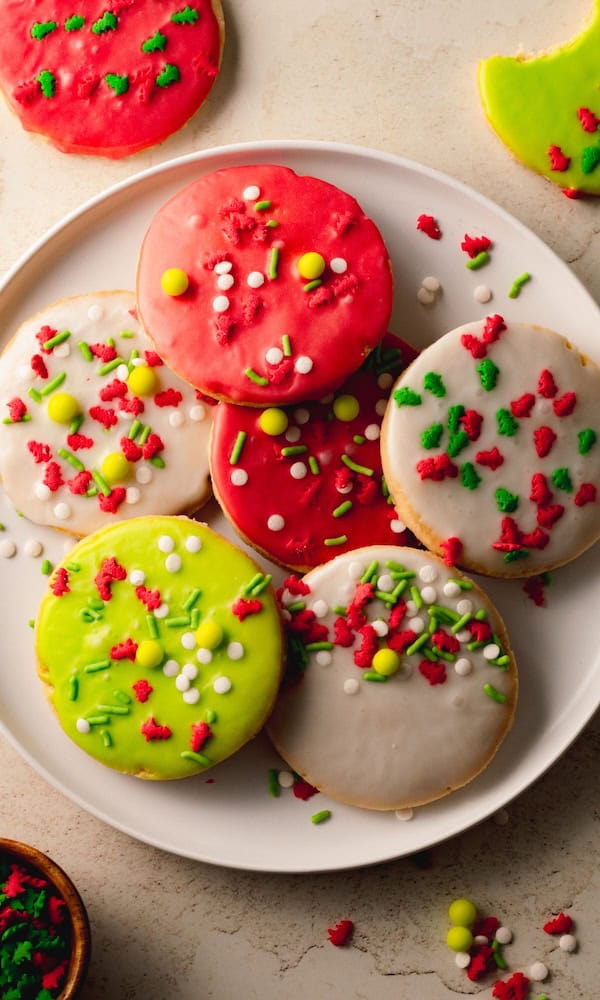 Christmas cut-out shortbread cookies topped with icing and colorful holiday sprinkles, arranged on a festive platter ready for the holiday cookie tray.