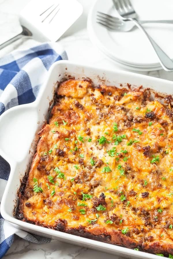Overnight breakfast casserole with sausage, bread cubes, eggs and cheddar in a baking dish — a make-ahead Christmas breakfast.