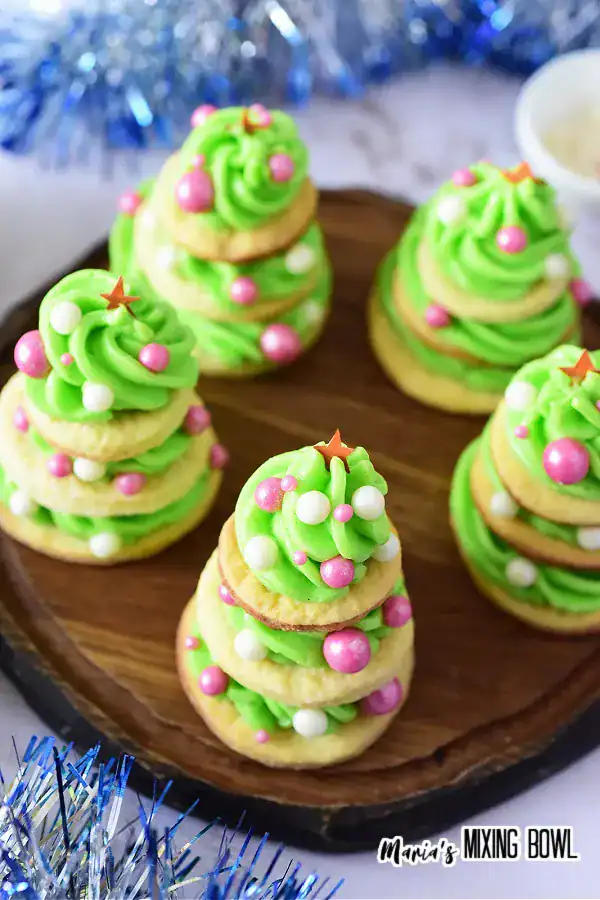 Festive frosted Christmas tree cookies stacked with green cream cheese frosting and sprinkles on top, homemade holiday sugar cookies for Christmas cookie trays.