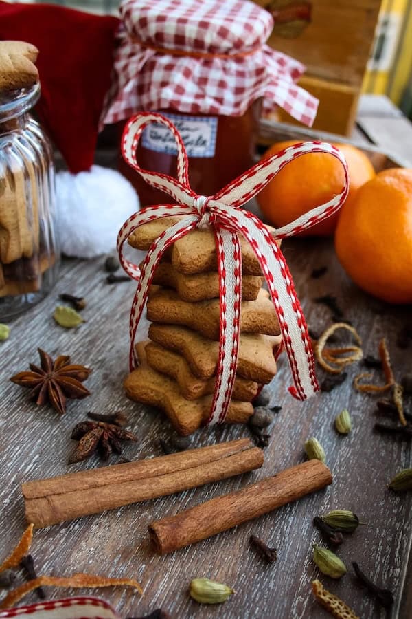 Star-shaped German Lebkuchen Christmas cookies with ginger and spice, displayed on a wooden board with holiday decorations for a festive homemade treat.