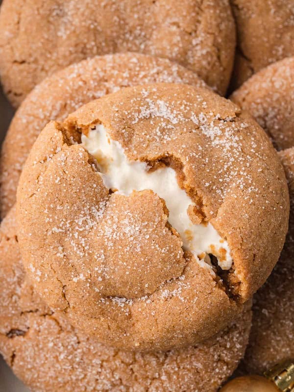 Soft gingerbread cheesecake cookies cut in half to show gooey cheesecake filling inside, arranged on a holiday platter for Christmas cookie display.