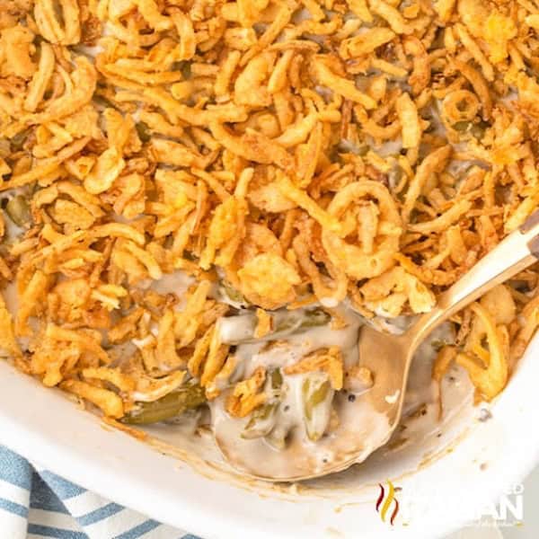 Creamy green bean casserole topped with crispy fried onions in a white baking dish — a make-ahead Christmas side dish.