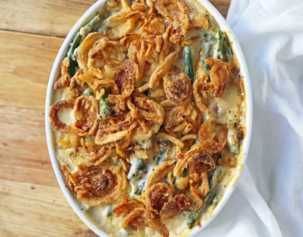 Homemade green bean casserole topped with crispy onions and creamy mushroom sauce — classic Christmas vegetable side dish.