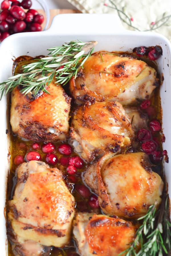 One-pan baked chicken thighs glazed in maple and topped with fresh cranberries and rosemary for a Christmas dinner.
