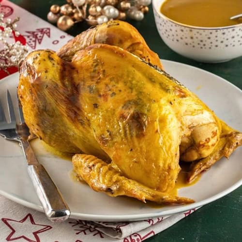 Whole roasted chicken stuffed with prunes and pine nuts, seasoned with rosemary, ready for Christmas dinner.