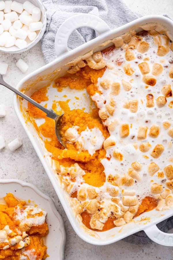 Sweet potato casserole topped with toasted marshmallows in a baking dish — decadent easy Christmas side dish.
