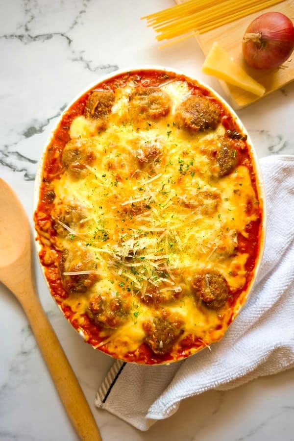 Golden-brown baked spaghetti and meatballs casserole with melted mozzarella and meatballs peeking through.