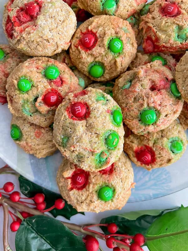 Colorful mini M&M-dotted gluten-free Christmas cookies on a white plate, a budget-friendly and festive holiday cookie treat.