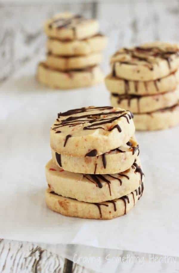 Chocolate shortbread cookies flecked with crushed peppermint candy and drizzled with dark chocolate, arranged neatly for a festive Christmas cookie platter.