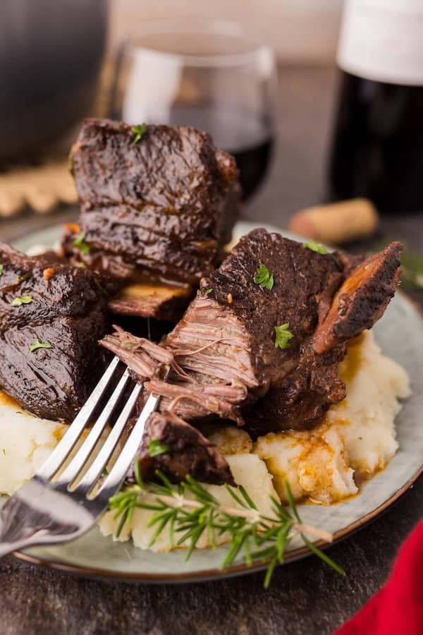 Braised beef short ribs in deep red wine sauce served on mashed potatoes for a festive Christmas dinner.