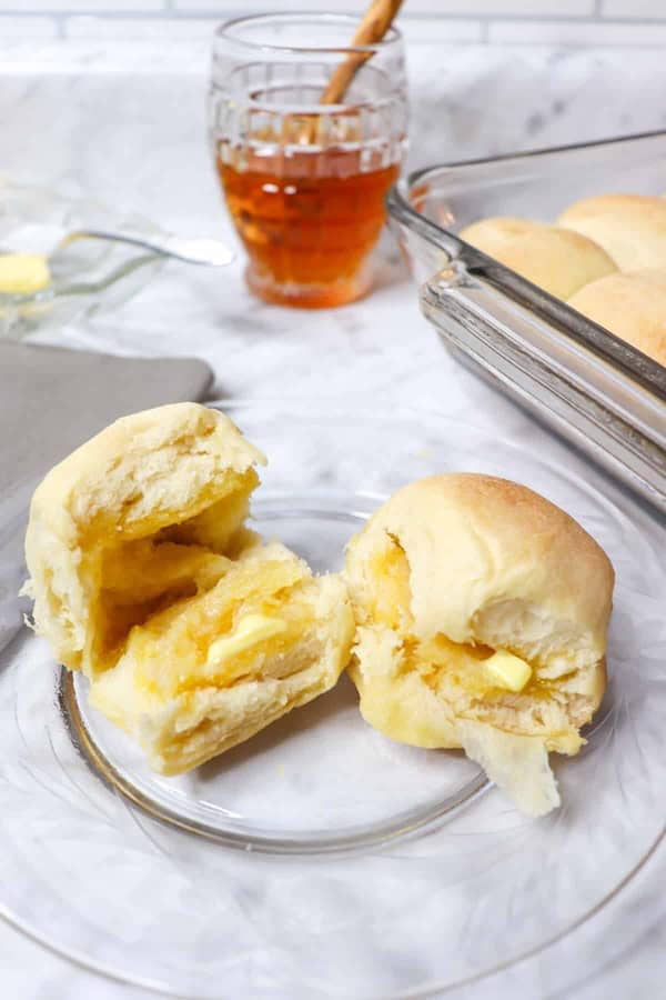 Two soft golden dinner rolls with melted butter — easy Christmas side dish for holiday gatherings.
