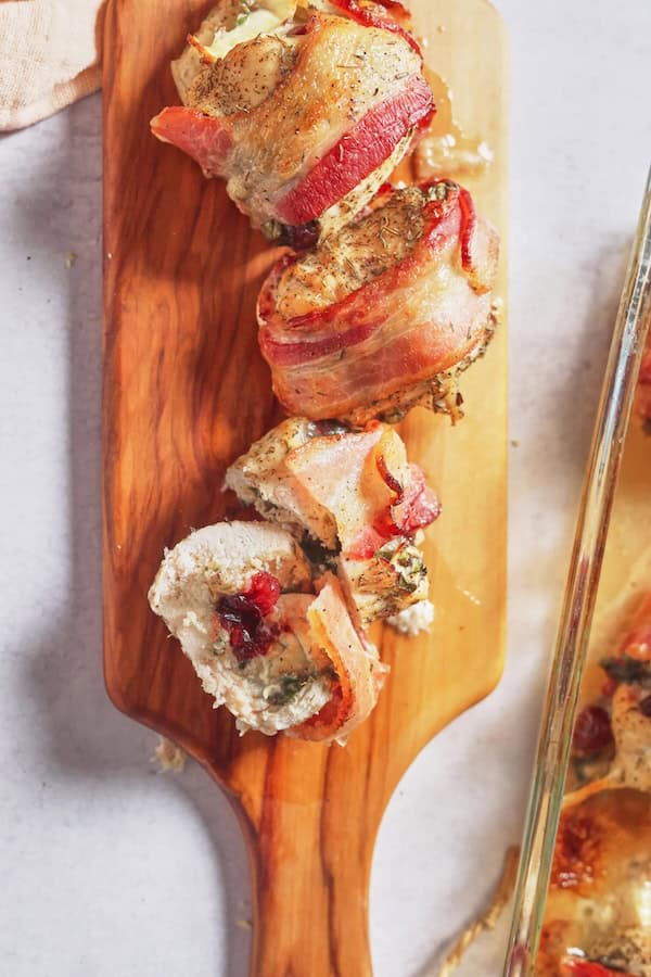 Bacon-wrapped chicken breast filled with melted brie and cranberry sauce ready for a Christmas dinner.
