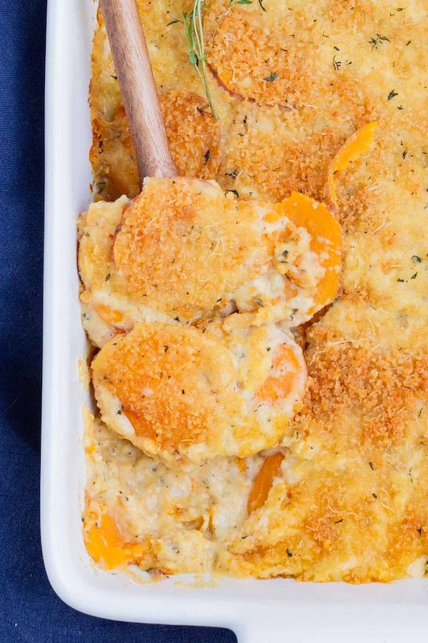 Sweet potato au gratin in a baking dish with melted cheese and breadcrumb topping — a make-ahead Christmas side dish.