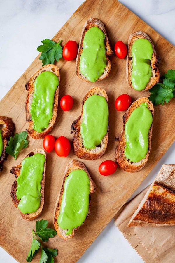 Creamy parsley and anchovy dip served with toasted baguette slices on a festive tray.