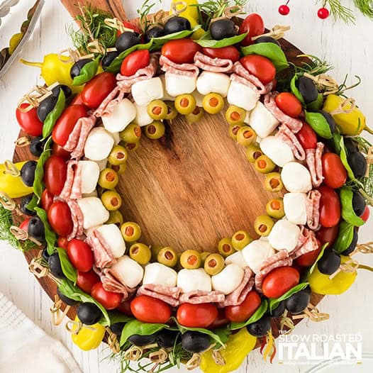 Antipasto wreath made of meats, cheeses, olives, and herbs shaped into a Christmas wreath.