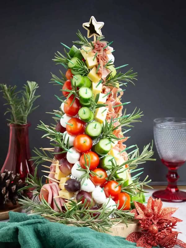 Christmas tree charcuterie board with meats, cheeses, and rosemary sprigs arranged in tree shape.