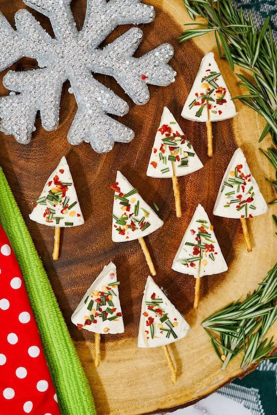 Festive Christmas tree cheese appetizer made with tomatoes, cheese cubes, and herbs on a holiday platter.