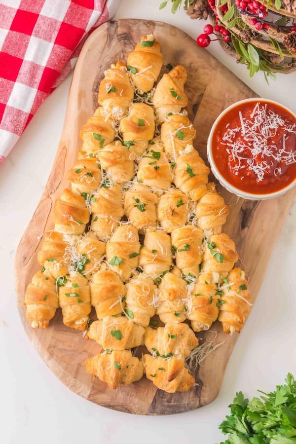 Cheese and olive Christmas tree appetizer platter decorated with rosemary sprigs.