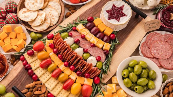 Christmas tree charcuterie board filled with cheese, meats, and rosemary sprigs for a festive look.