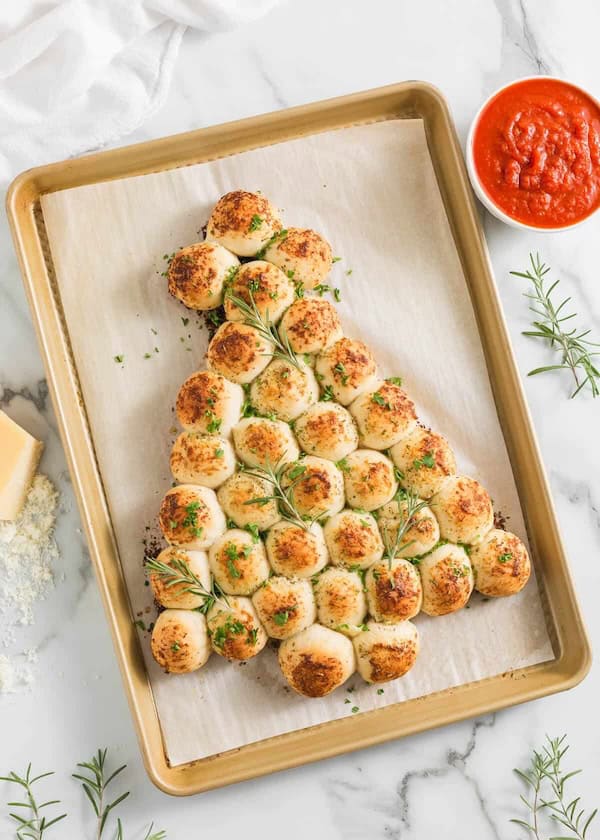 Cheesy pull-apart bread arranged like a Christmas tree with herbs and melted cheese.
