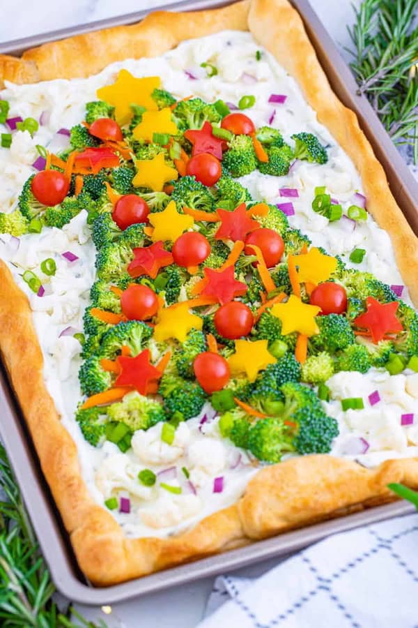 Crescent roll veggie pizza shaped like a Christmas tree topped with colorful vegetables.