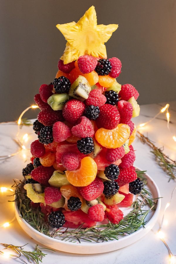 Fresh fruit Christmas tree made of strawberries, kiwi, and grapes arranged in a tree shape.