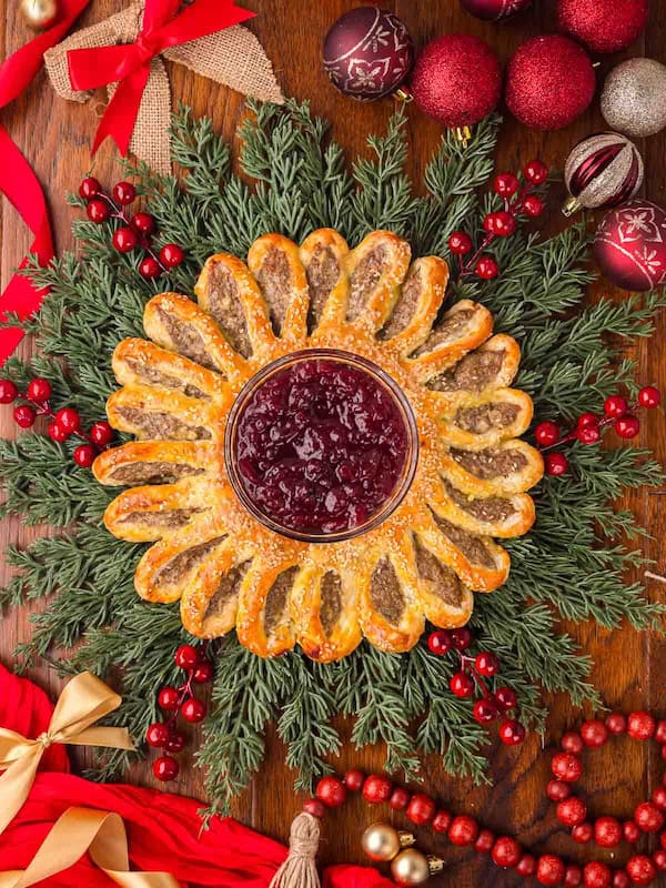 Puff pastry sausage roll wreath baked golden brown and served with dipping sauce.