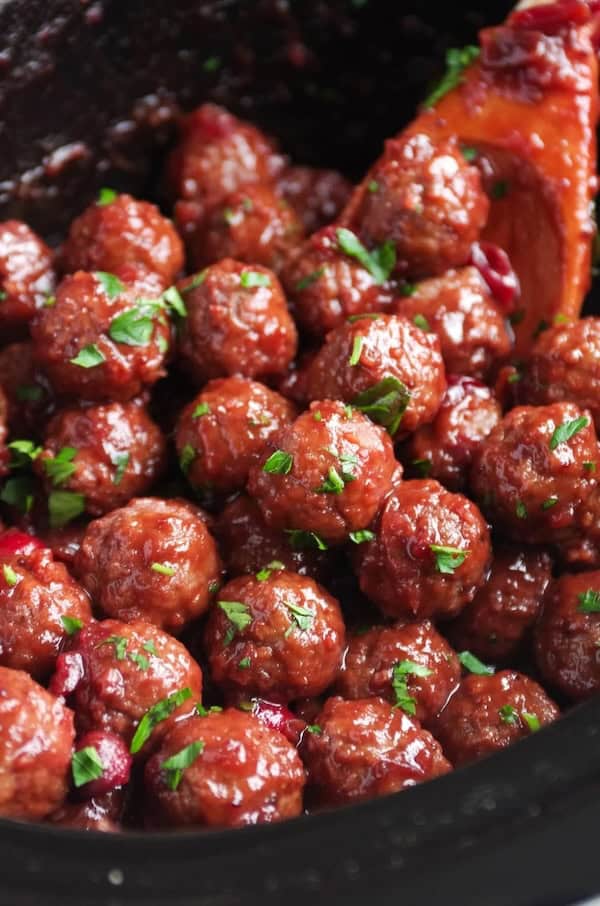 Crockpot cranberry meatballs glazed in sweet sauce and topped with fresh herbs — holiday appetizer.