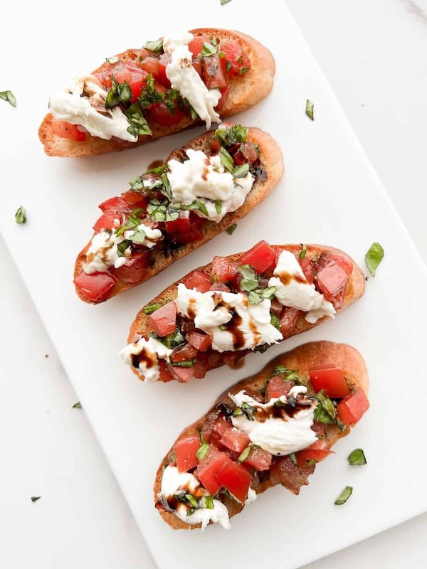 Burrata bruschetta with tomatoes and basil on toasted bread served as an elegant holiday appetizer.