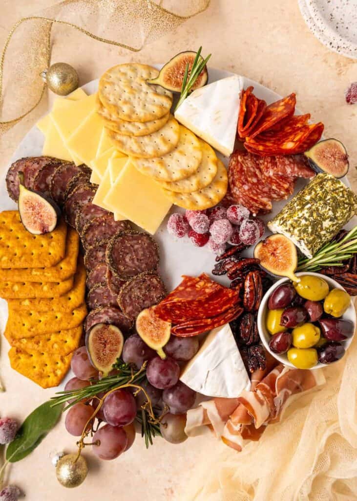Charcuterie wreath with meats, cheeses, olives, and herbs arranged in a holiday wreath shape.