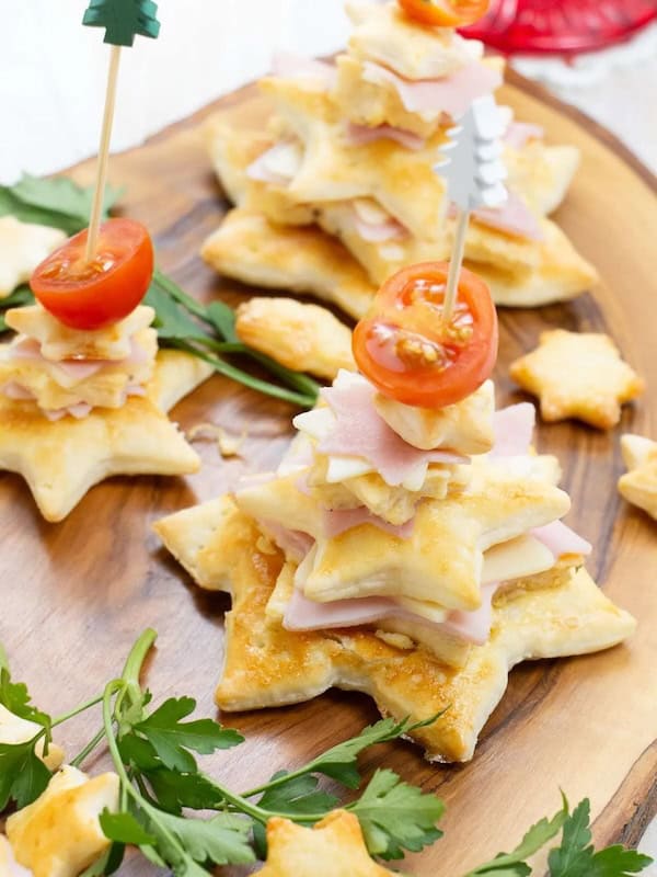 Christmas tree charcuterie board with meats, cheeses, and rosemary sprigs arranged in tree shape.