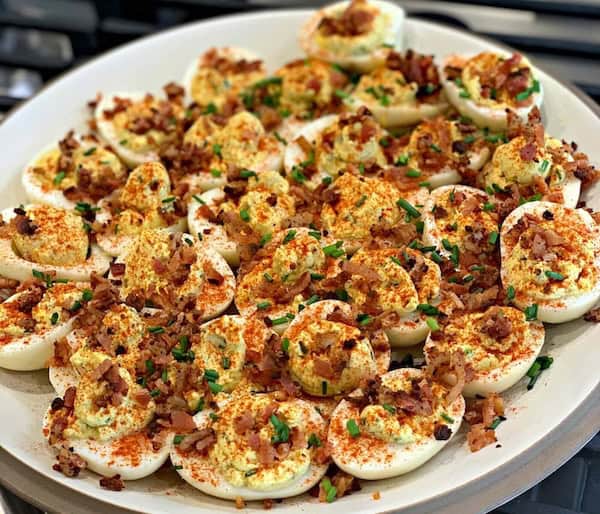 Smoked deviled eggs arranged on a festive holiday serving platter with paprika and herbs — perfect easy Christmas appetizer idea.