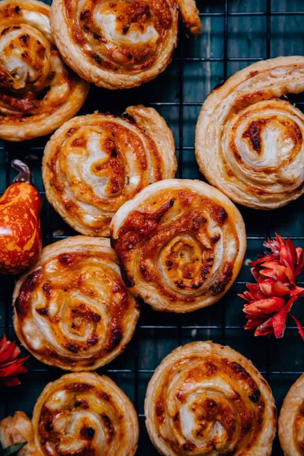 Pumpkin pinwheels made with puff pastry spirals on a white serving board.