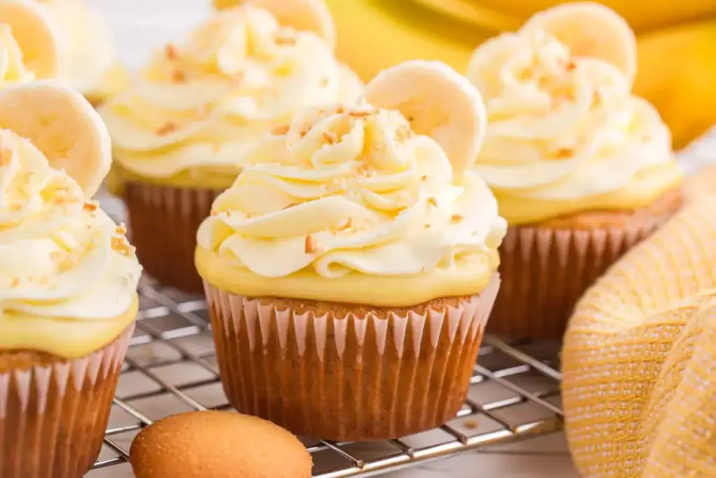 Banana pudding cupcakes with creamy frosting and vanilla wafer topping on a tray