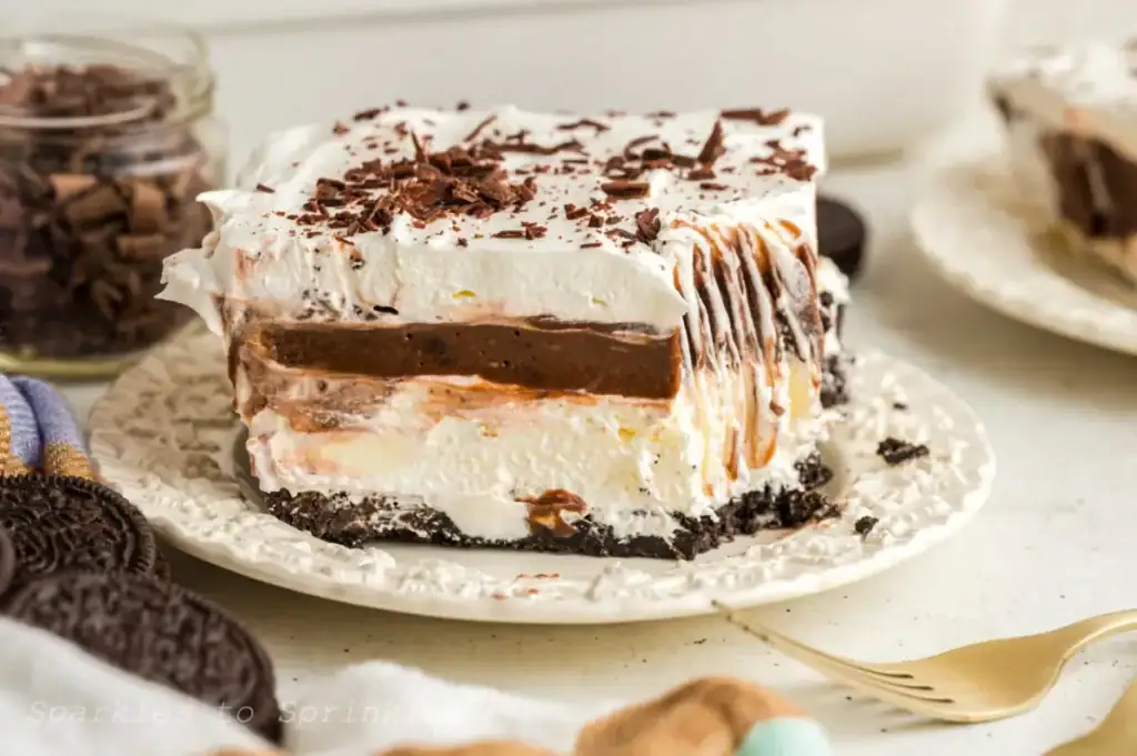 Chocolate lasagna dessert with layered cream, pudding, and cookie crust in a glass dish
