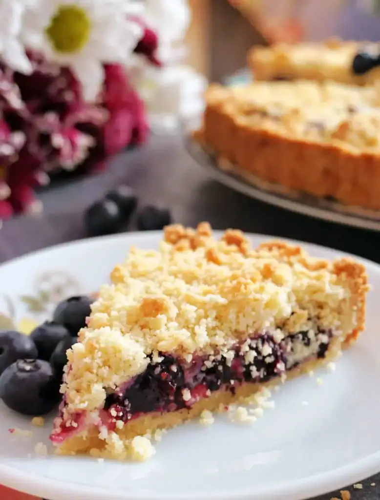 Blueberry crumble pie slice with juicy filling and golden crumb topping on a plate