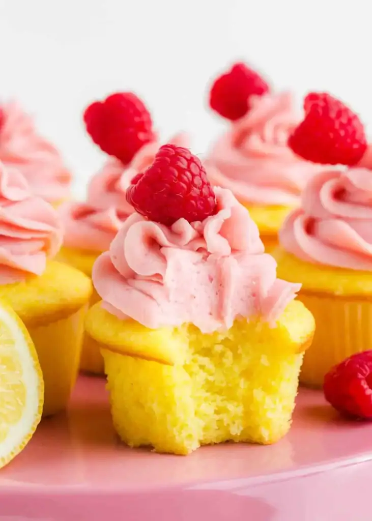 Lemon raspberry cupcakes topped with frosting and fresh raspberries