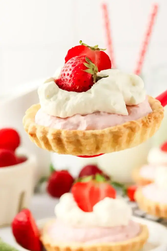 Mini strawberry mousse tartlets topped with fresh berries and powdered sugar