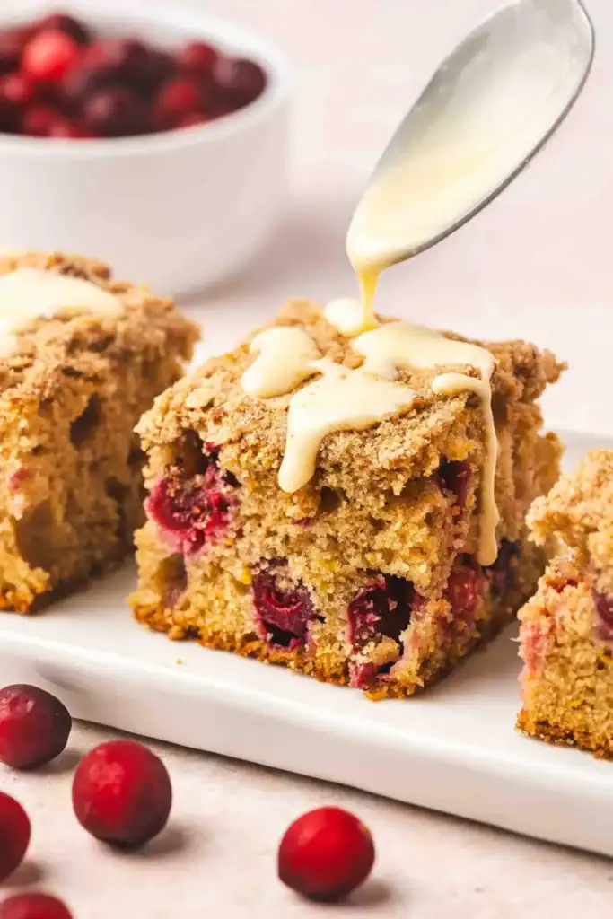 Cranberry orange coffee cake slice with streusel topping and orange glaze on a plate
