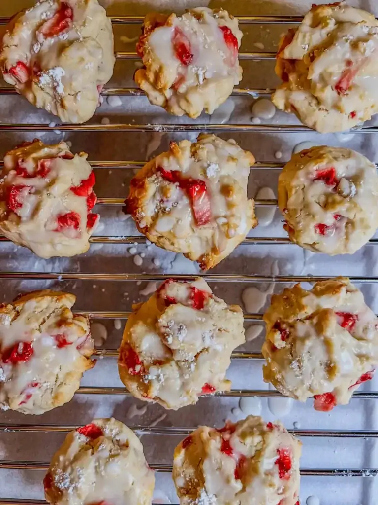 strawberry scone cookies with lemon icing drizzled on top on a serving plate